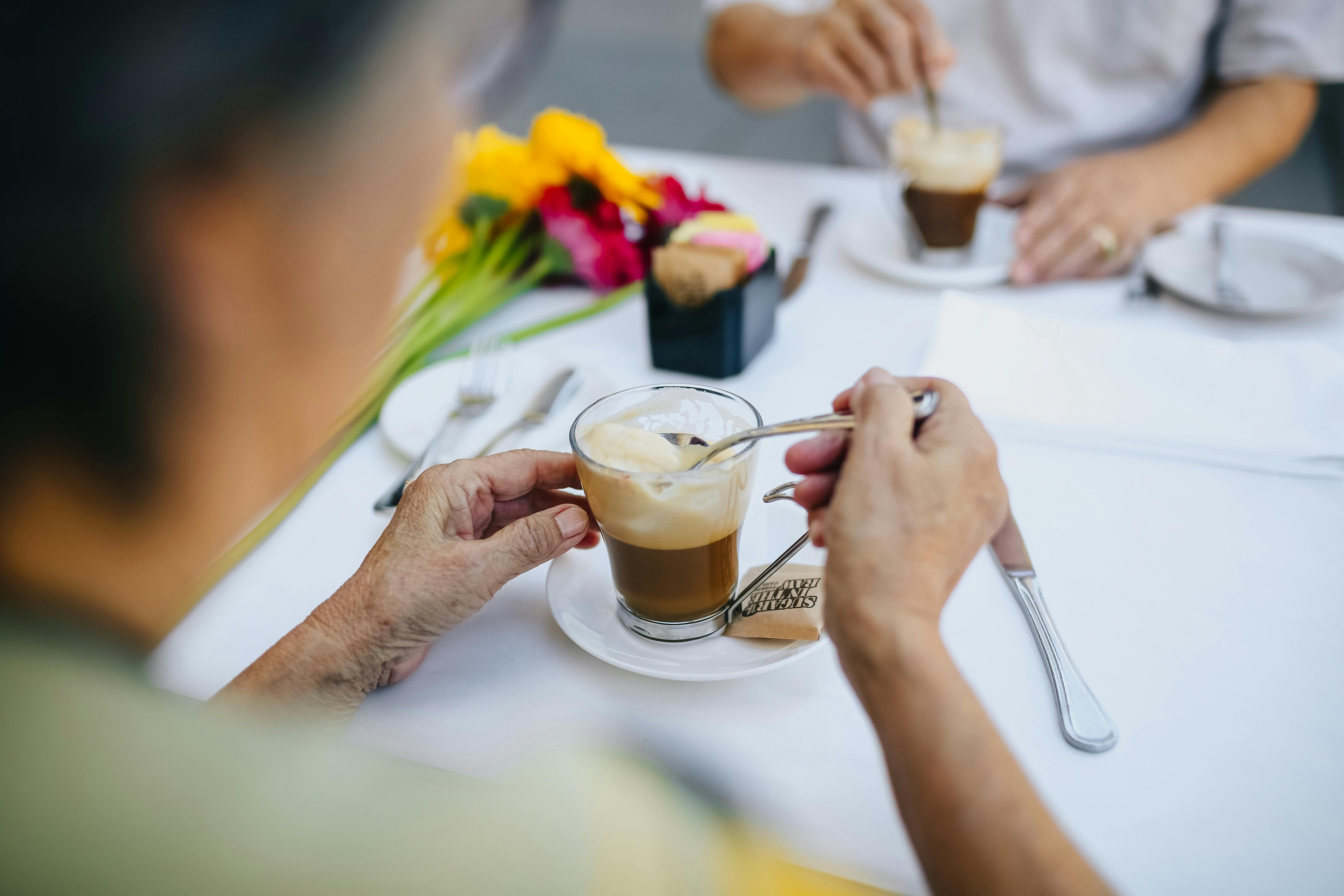 Two people enjoying coffee at a cafe table with fresh flowers — everyday life abroad as a retiree